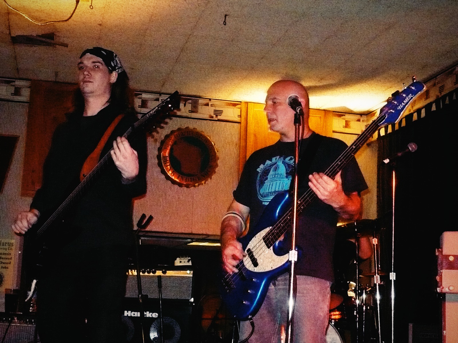 Alexei and Matt performing live onstage in an early Pistols at Dawn lineup, showing guitar, bass, and stage equipment